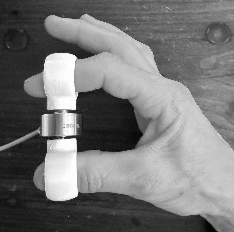 Splayometer finger rings in use: one ring on the target finger, one on the thumb, for single-digit extension measurement.