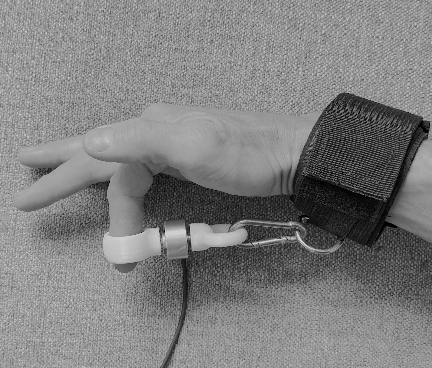 Splayometer finger rings in use: one ring on the target finger, one on the thumb, for single-digit extension measurement.
