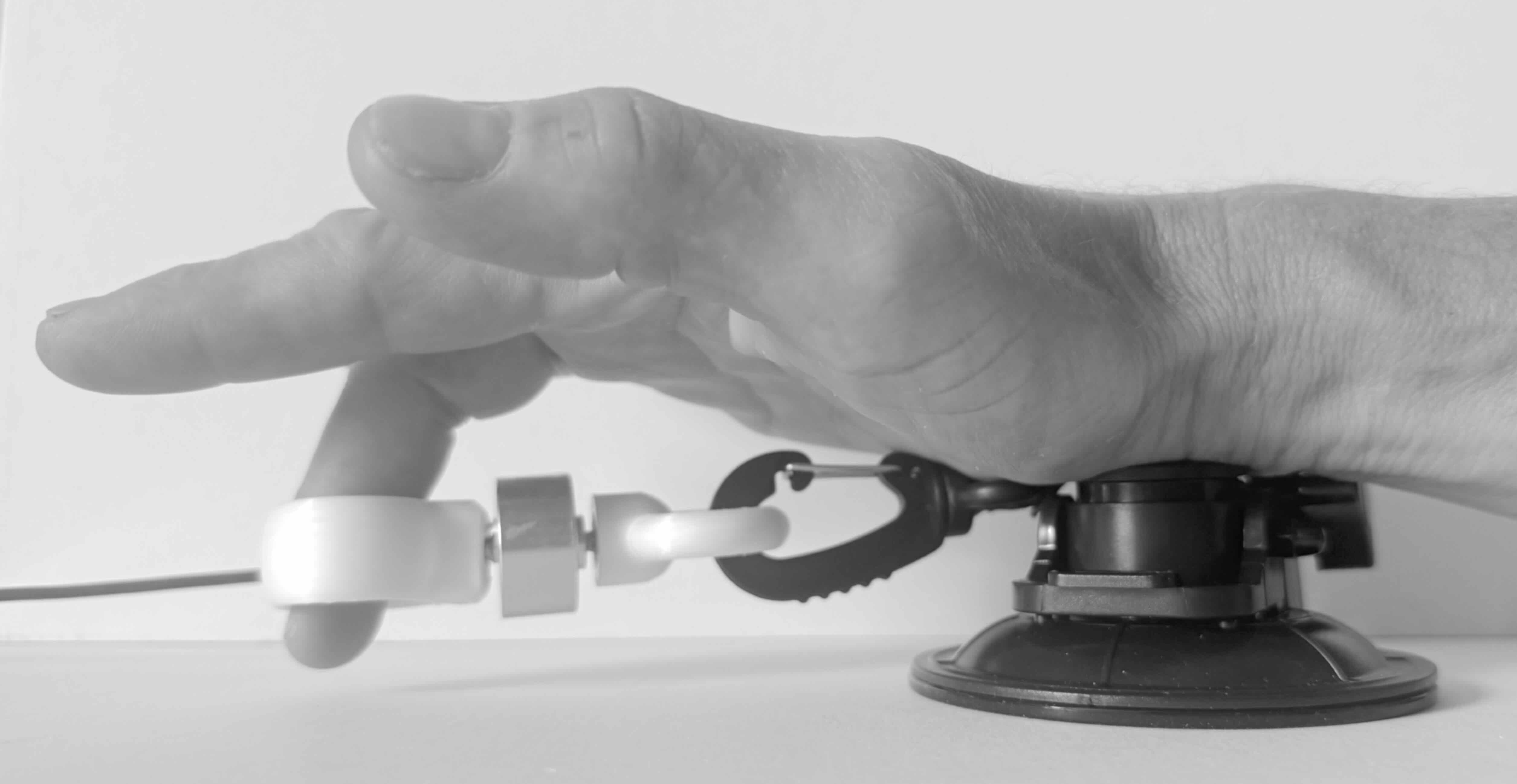 Splayometer finger ring on the middle finger, with the load cell clipped to a suction cup anchor on the table, for single finger extension.